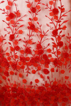 a close-up view of a fabric with a floral pattern of red roses and leaves. The roses are arranged in a repeating pattern, creating a visually striking and intricate design. The leaves are also arranged in a similar manner, adding to the overall aesthetic of the fabric. The image does not contain any text or other discernible objects, and the focus is solely on the floral pattern.