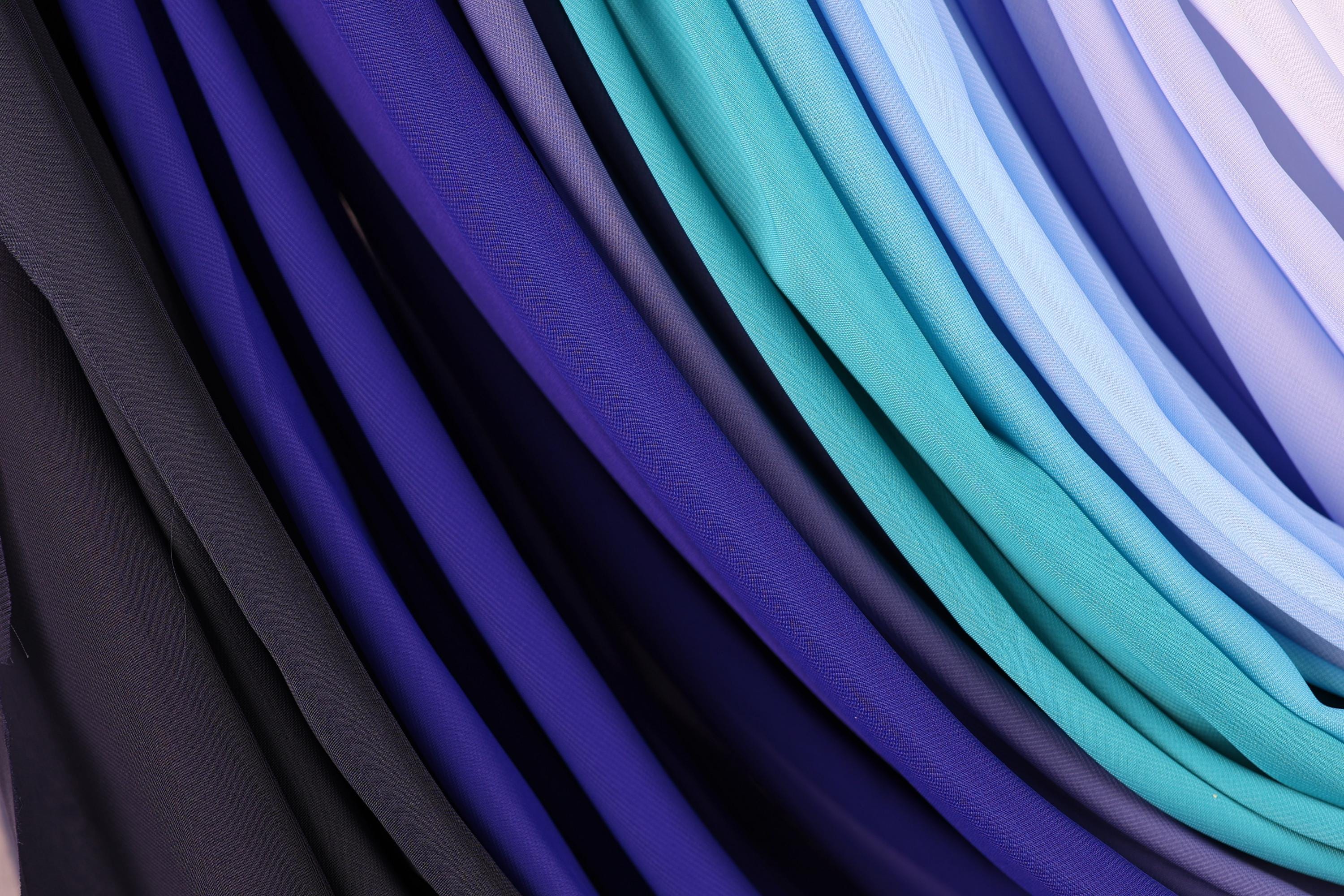 a close-up view of a collection of fabric swatches in various shades of blue, purple, and black.