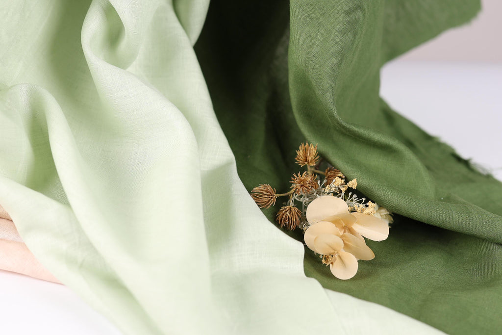 a close-up view of a green fabric with a delicate flower resting on it.