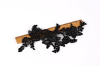 a wooden ruler with black lace or fabric attached to it, placed on a white background.