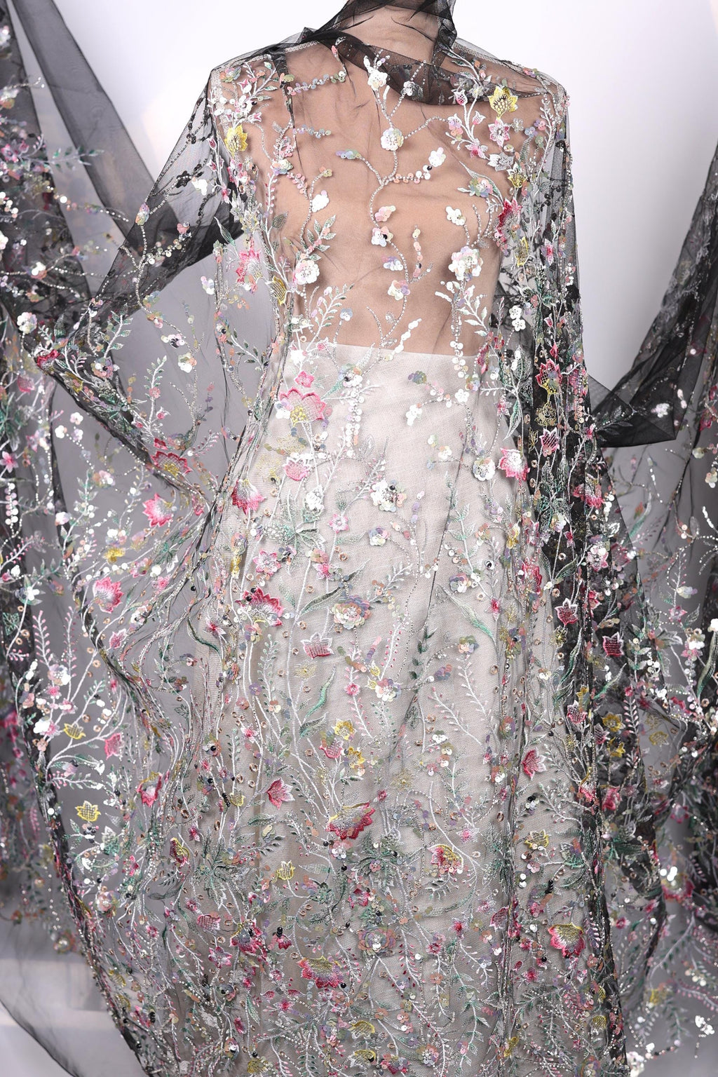 a dress with a sheer, floral-patterned fabric draped over the body. The dress appears to be made of a sheer material, giving it a delicate and airy appearance. The floral pattern is intricate and detailed, adding a touch of elegance and sophistication to the overall design.