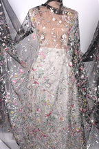 a dress with a sheer, floral-patterned fabric draped over the body. The dress appears to be made of a sheer material, giving it a delicate and airy appearance. The floral pattern is intricate and detailed, adding a touch of elegance and sophistication to the overall design.