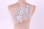 A mannequin with a delicate floral embroidered on its chest against a pink background.