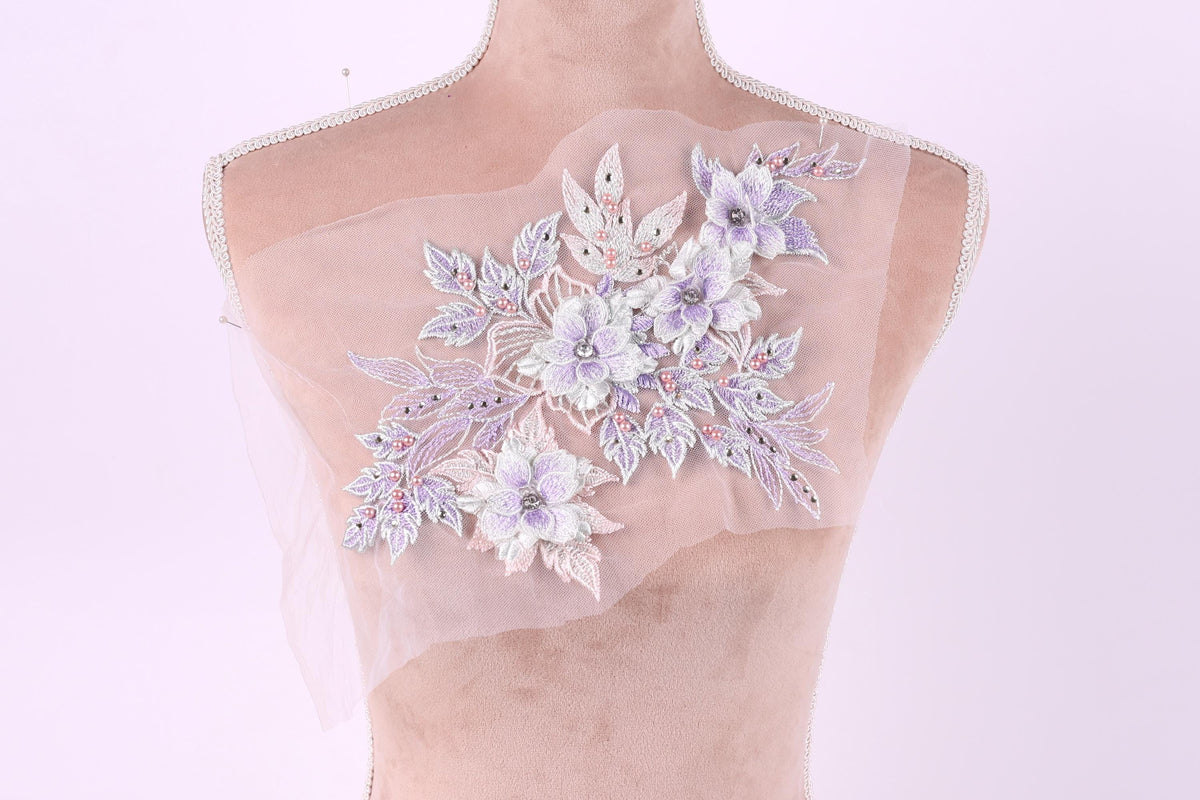 A mannequin with a delicate floral embroidered on its chest against a pink background.