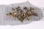 a close-up view of a piece of fabric with a floral pattern, including gold and black flowers, placed on a transparent ruler.