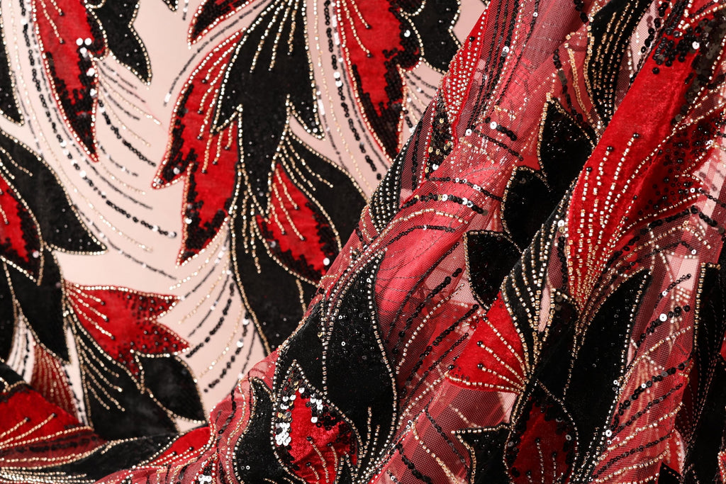 a close-up view of a fabric with a striking pattern of red, black, and white sequins and beads. The fabric appears to be a sheer material, with the intricate design and texture creating a visually appealing and eye-catching piece.