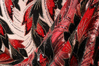 a close-up view of a fabric with a striking pattern of red, black, and white sequins and beads. The fabric appears to be a sheer material, with the intricate design and texture creating a visually appealing and eye-catching piece.