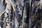 The image is a close-up of a fabric with a floral pattern, featuring blue and black colors and gold accents.