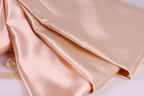 a close-up view of a soft, light-colored fabric, possibly silk or satin, with a smooth and shiny texture.