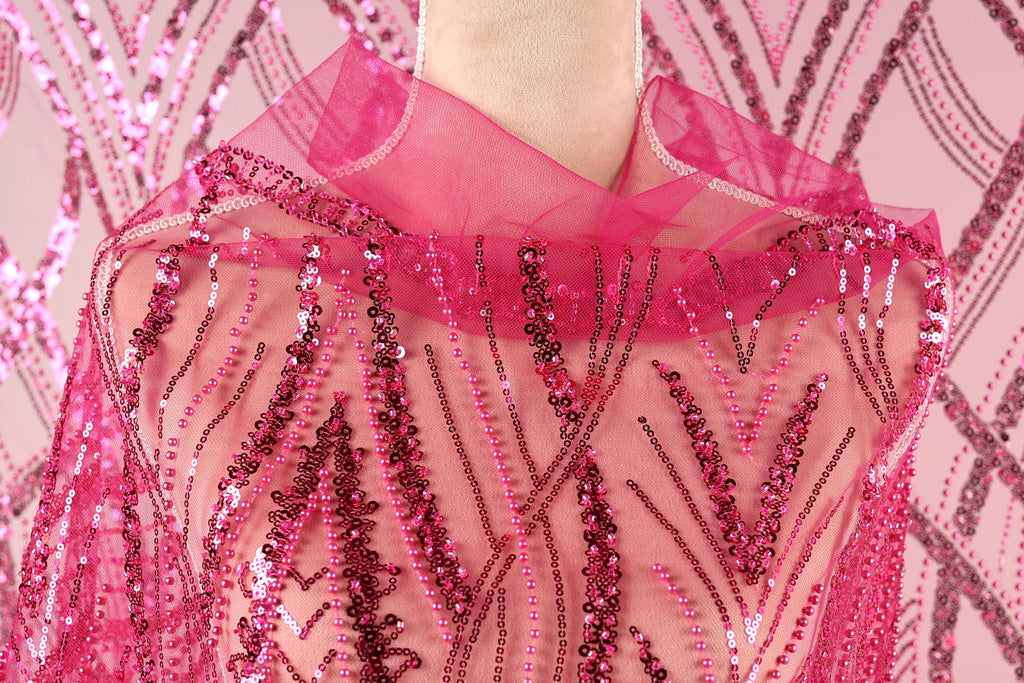 A close-up view of a mannequin wearing a pink sequin shawl or cape.