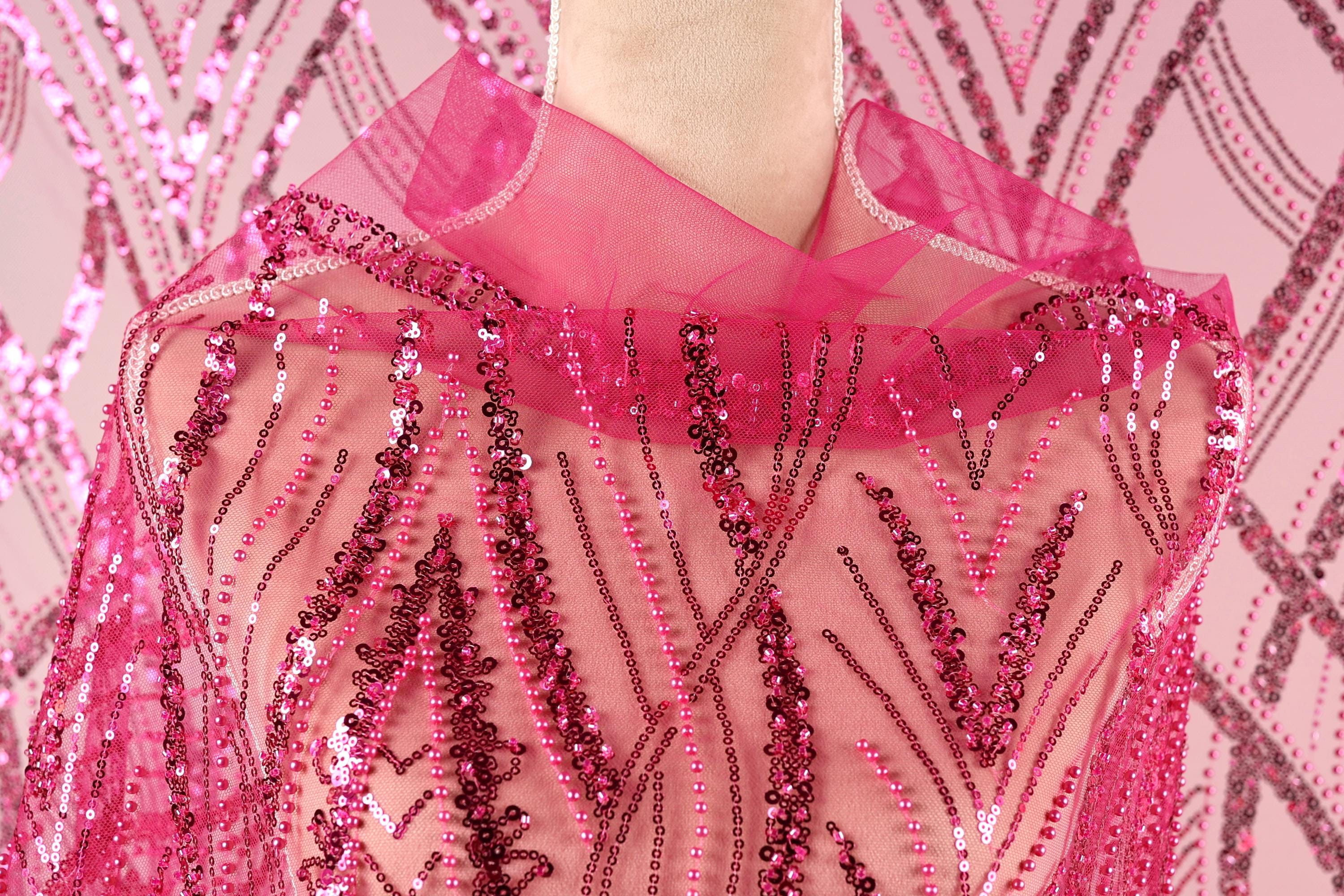 A close-up view of a mannequin wearing a pink sequin shawl or cape.