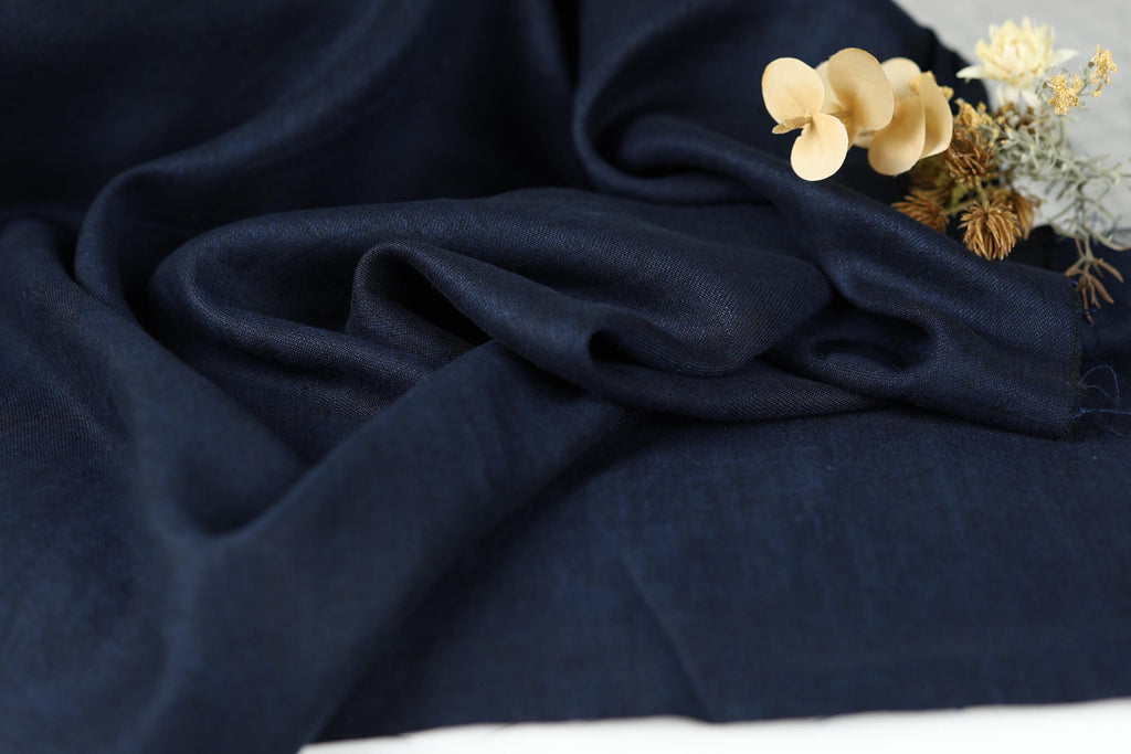a close-up view of a dark blue fabric, with a small bouquet of white flowers resting on top of it.