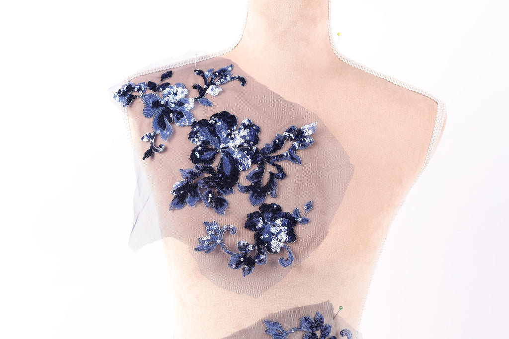 A mannequin with a decorative fabric piece featuring blue floral embroidery on its shoulder.