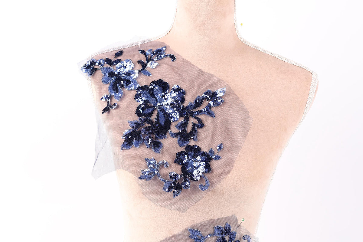 A mannequin with a decorative fabric piece featuring blue floral embroidery on its shoulder.