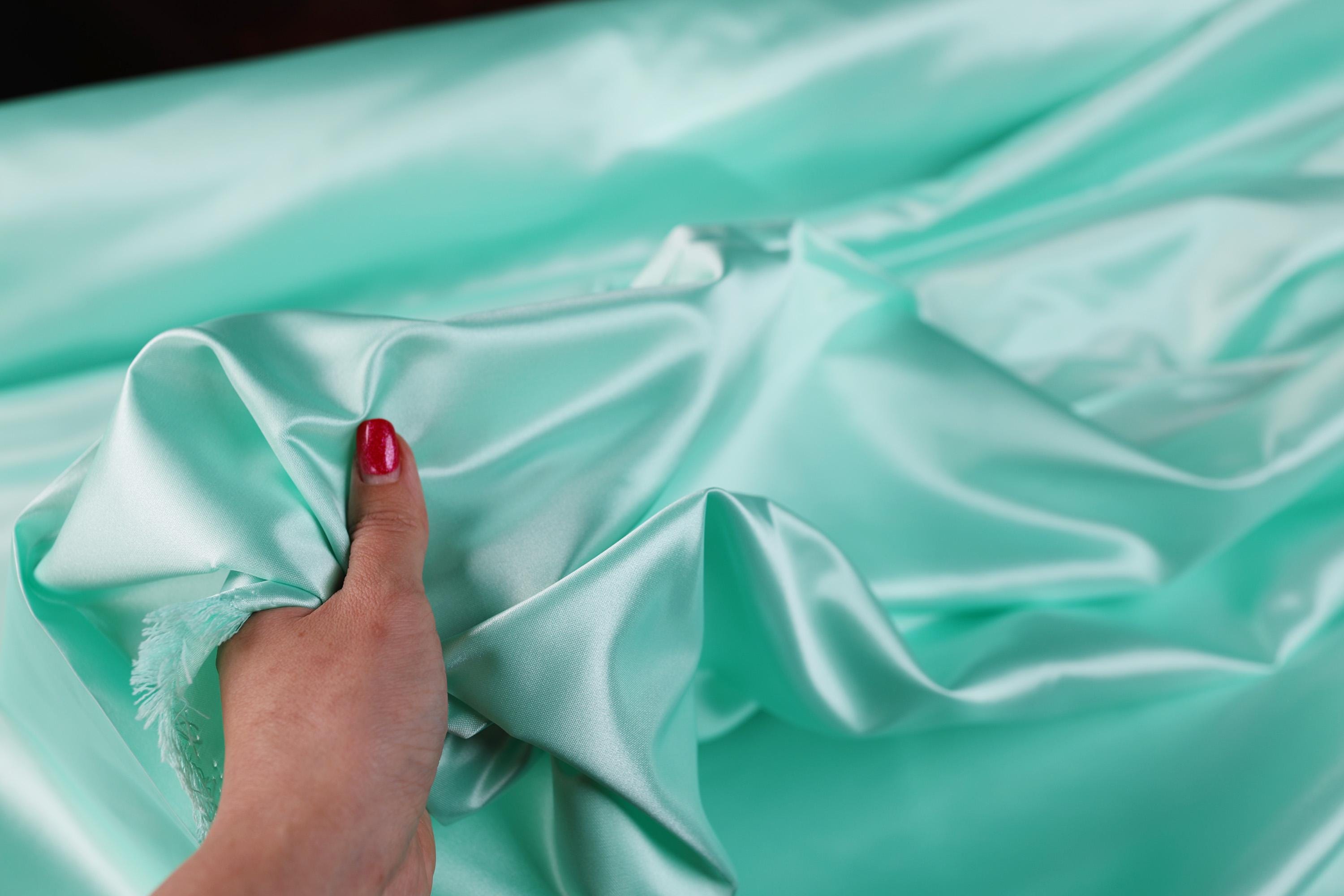 a woman's hand with a red nail polish polishing the fabric of a