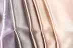 A close-up image of a fabric with a gradient of colors, transitioning from a light pink to a darker pink to a light gray.