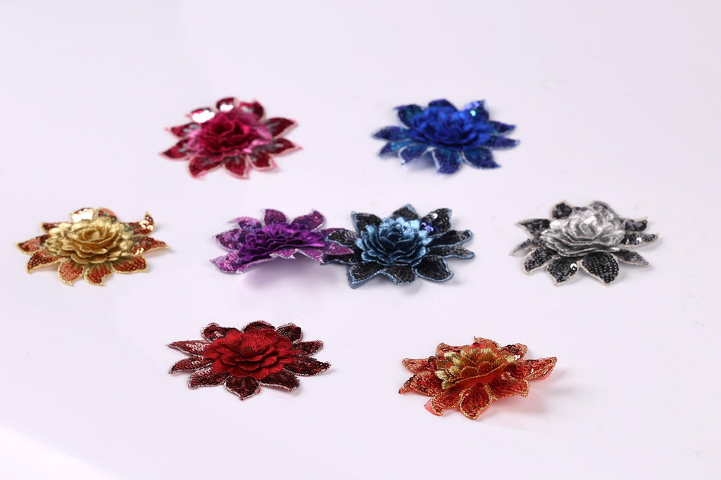 seven colorful flower-shaped embellishments arranged in a grid-like pattern on a white background.