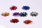 seven colorful flower-shaped embellishments arranged in a grid-like pattern on a white background.