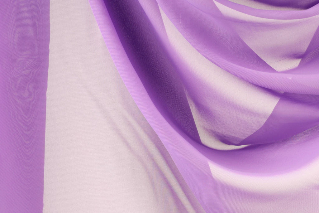 a close-up view of a fabric with a purple and white color scheme. The fabric appears to be made of sheer material, with a soft and flowing texture. The colors are vibrant and the fabric appears to be made of silk or chiffon, creating a visually appealing and elegant appearance.