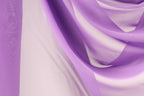 a close-up view of a fabric with a purple and white color scheme. The fabric appears to be made of sheer material, with a soft and flowing texture. The colors are vibrant and the fabric appears to be made of silk or chiffon, creating a visually appealing and elegant appearance.