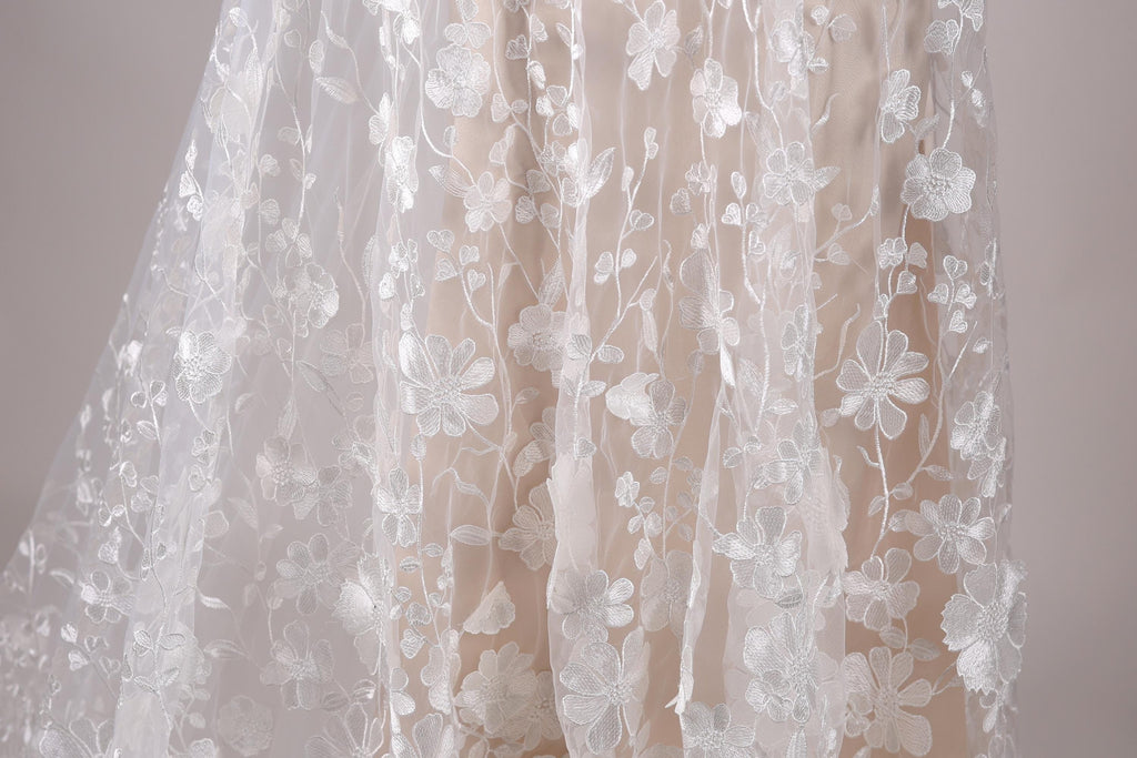 a close-up view of a delicate, white lace dress with a floral pattern.