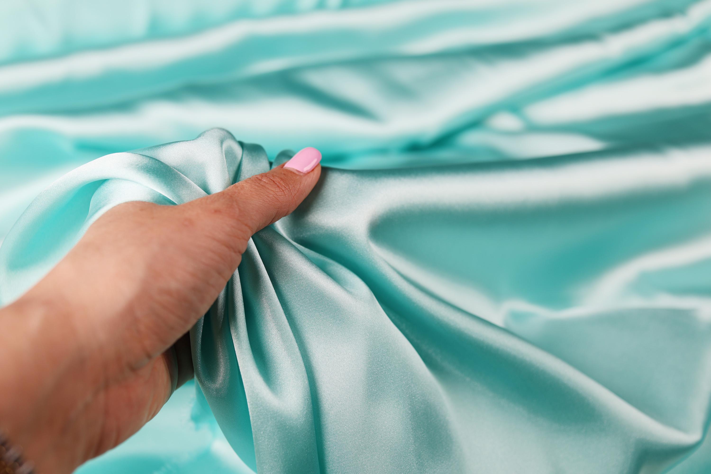 a woman&#39;s hand holding a satin material