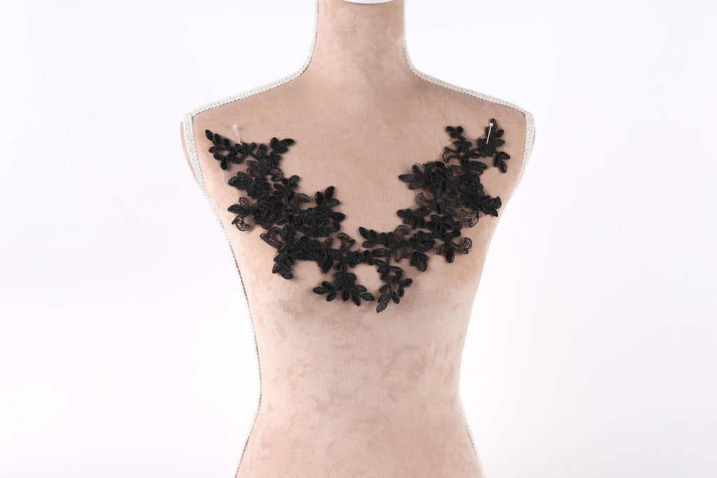 A mannequin wearing a black lace necklace with a floral pattern.