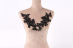 A mannequin wearing a black lace necklace with a floral pattern.