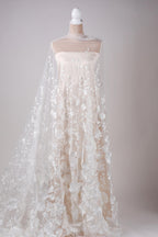 A white wedding dress with a long, flowing veil draped over it, displayed on a mannequin.