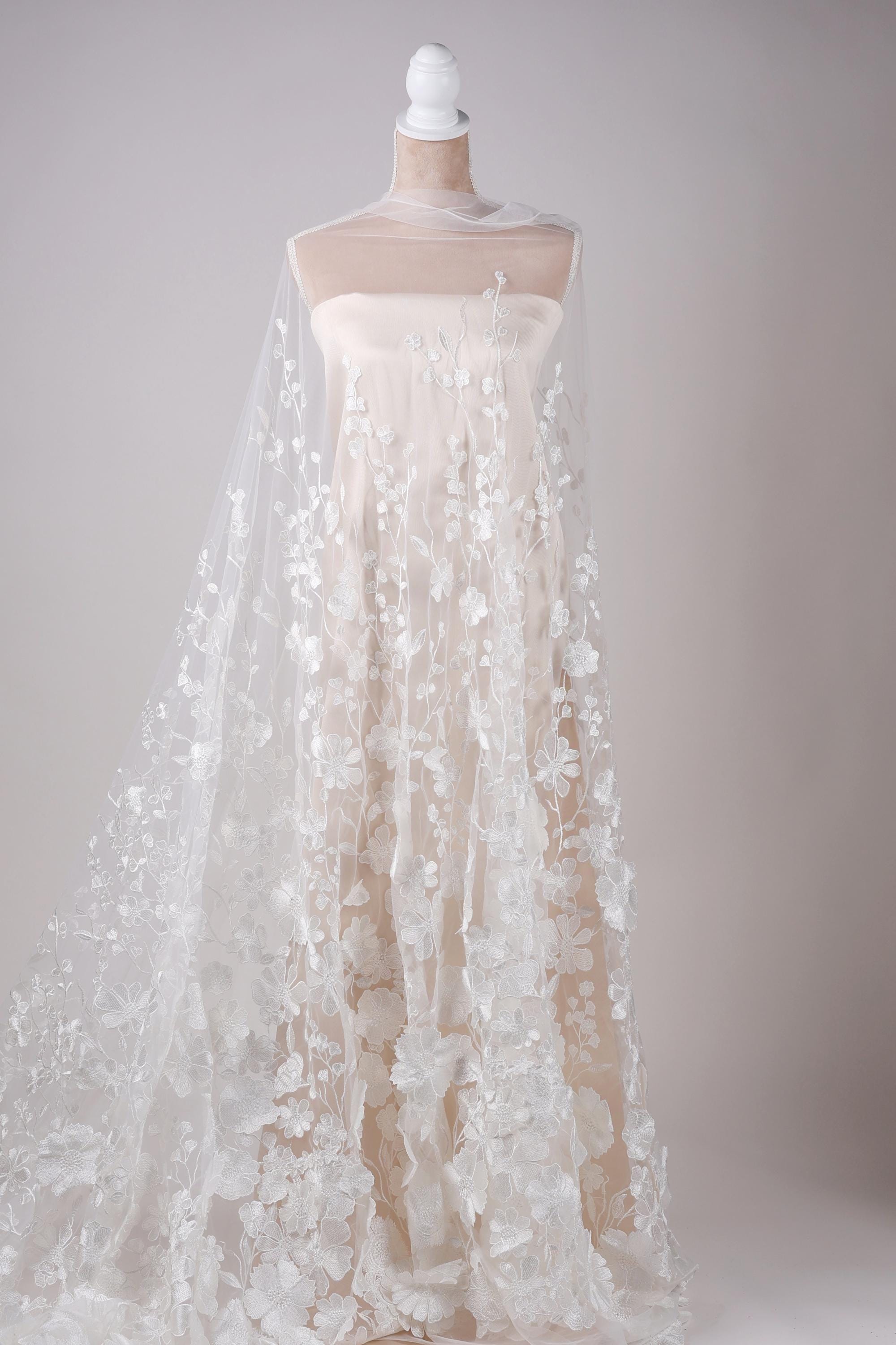 A white wedding dress with a long, flowing veil draped over it, displayed on a mannequin.