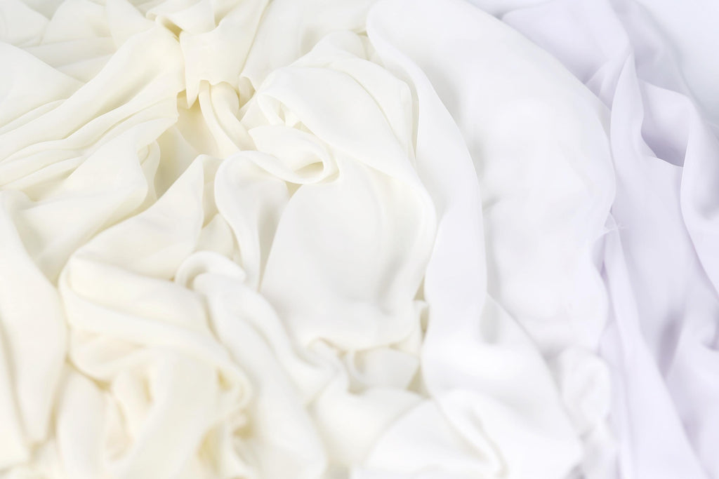 The image is a close-up of a white fabric with a subtle purple hue, creating a soft and delicate appearance.