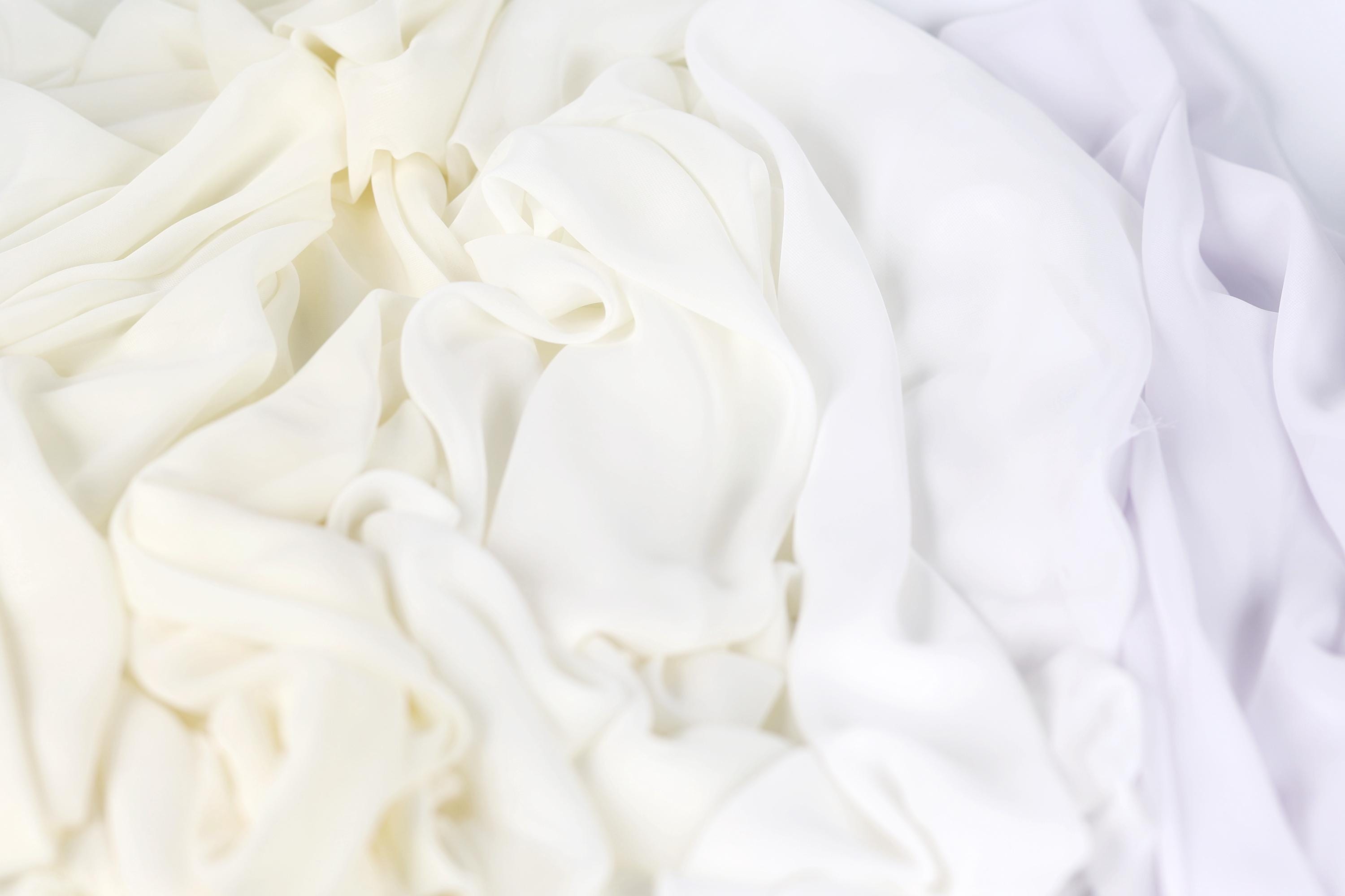 The image is a close-up of a white fabric with a subtle purple hue, creating a soft and delicate appearance.