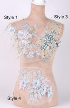 A mannequin with various decorative fabric pieces attached to its torso, including floral and leaf-like patterns in different colors.