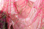 a close-up view of a pink and gold sequined fabric, with intricate patterns and designs.