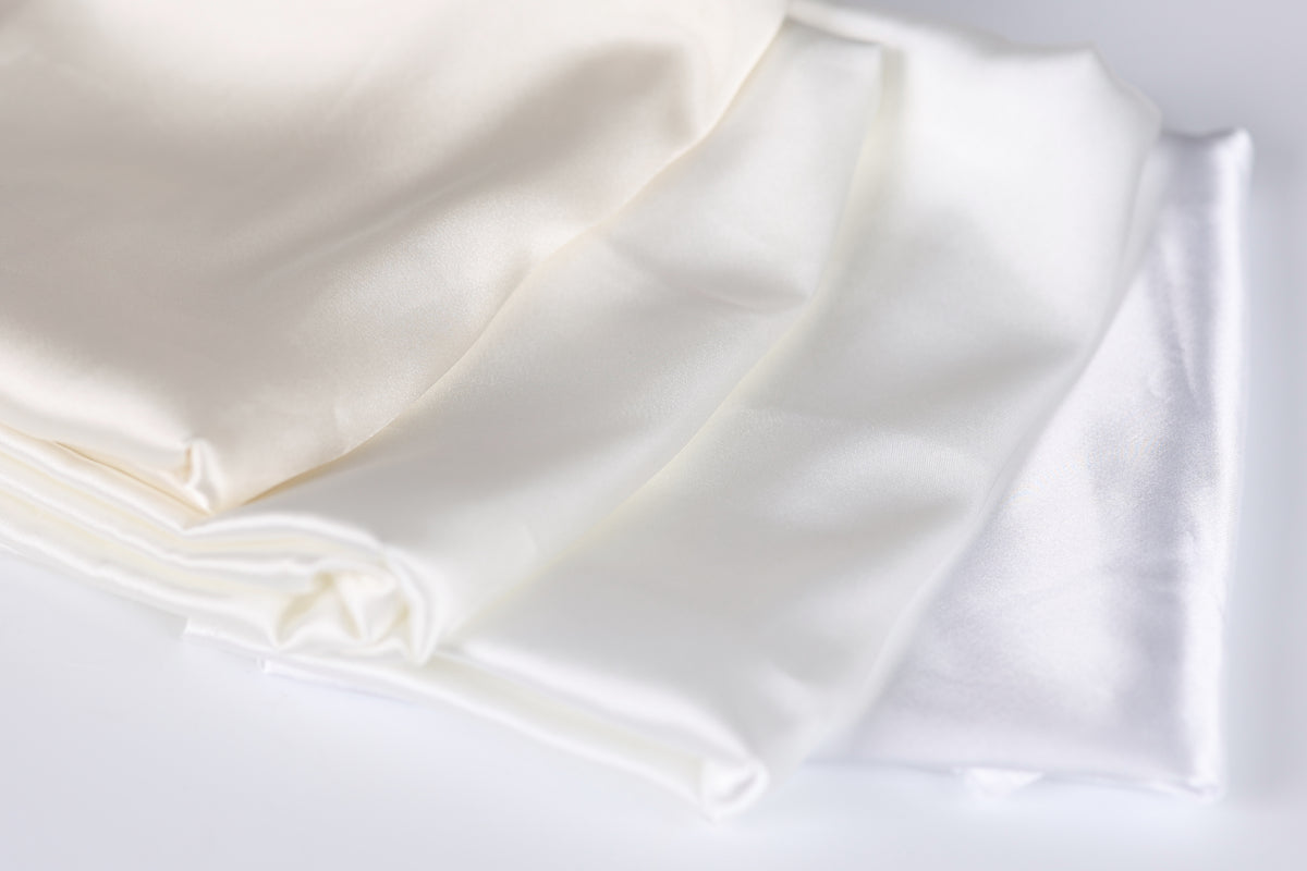 a close-up view of a white fabric, possibly silk or satin, with a slightly wrinkled texture.