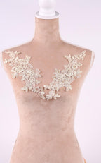 A mannequin wearing a beige dress with a delicate lace overlay on the neckline.