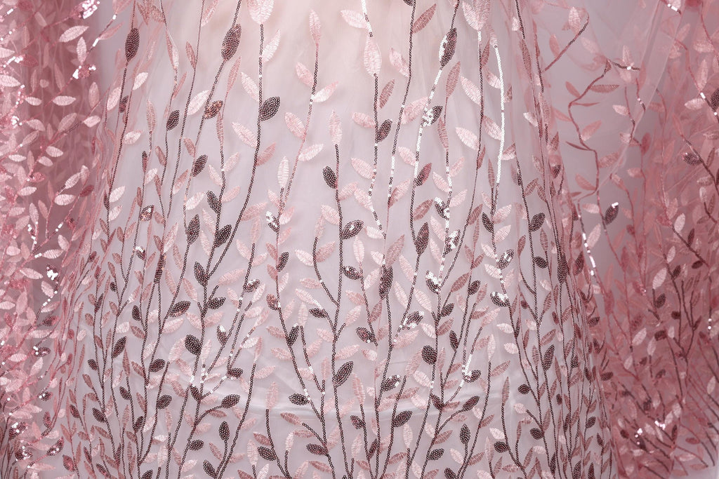 a close-up view of a fabric with a delicate floral pattern, including pink and brown leaves and branches. The fabric appears to be made of a sheer material, giving it a delicate and airy appearance.