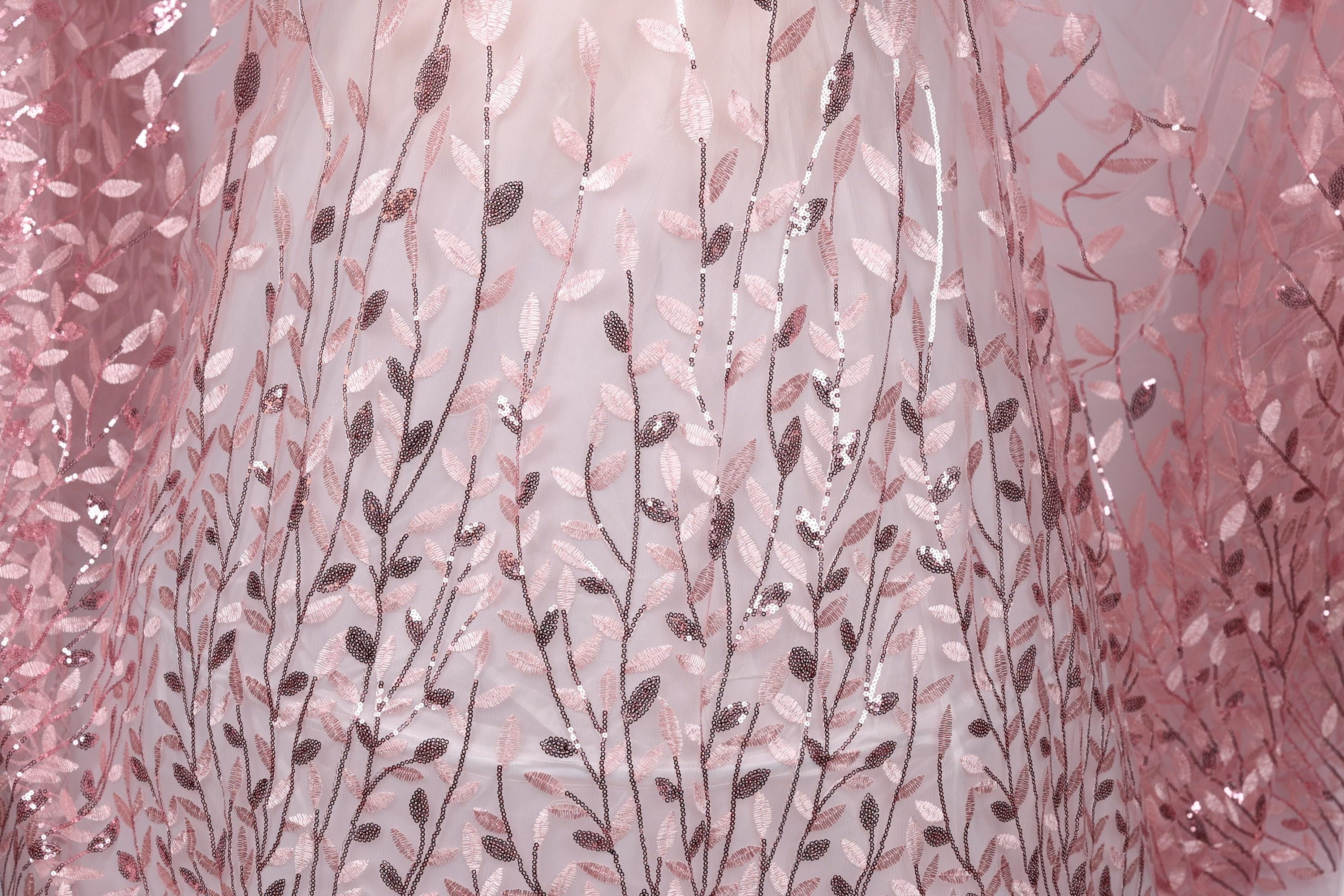 a close-up view of a fabric with a delicate floral pattern, including pink and brown leaves and branches. The fabric appears to be made of a sheer material, giving it a delicate and airy appearance.