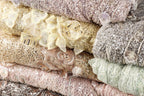 A close-up image of various colorful and intricately designed fabric pieces, including sequins and lace, stacked on top of each other.
