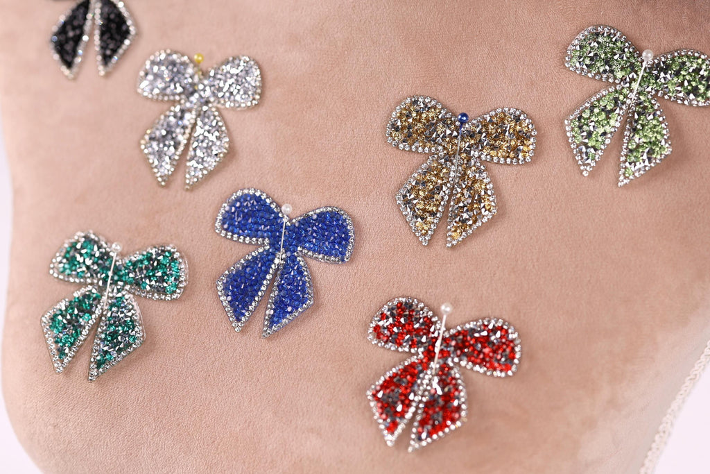 a close-up view of a person's arm adorned with a variety of colorful, sparkling rhinestone-encrusted bows.