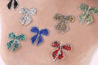 a close-up view of a person's arm adorned with a variety of colorful, sparkling rhinestone-encrusted bows.