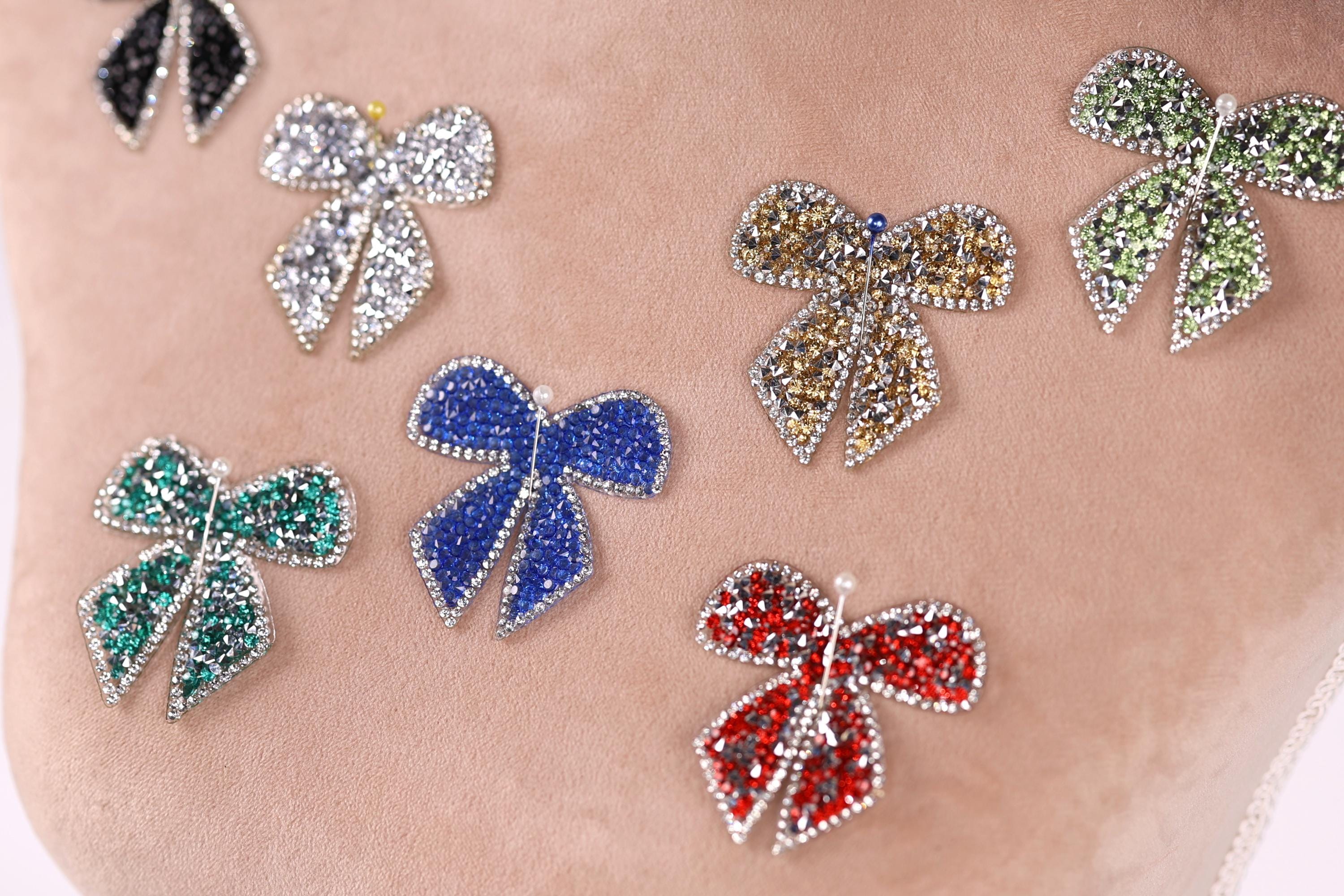 a close-up view of a person's arm adorned with a variety of colorful, sparkling rhinestone-encrusted bows.