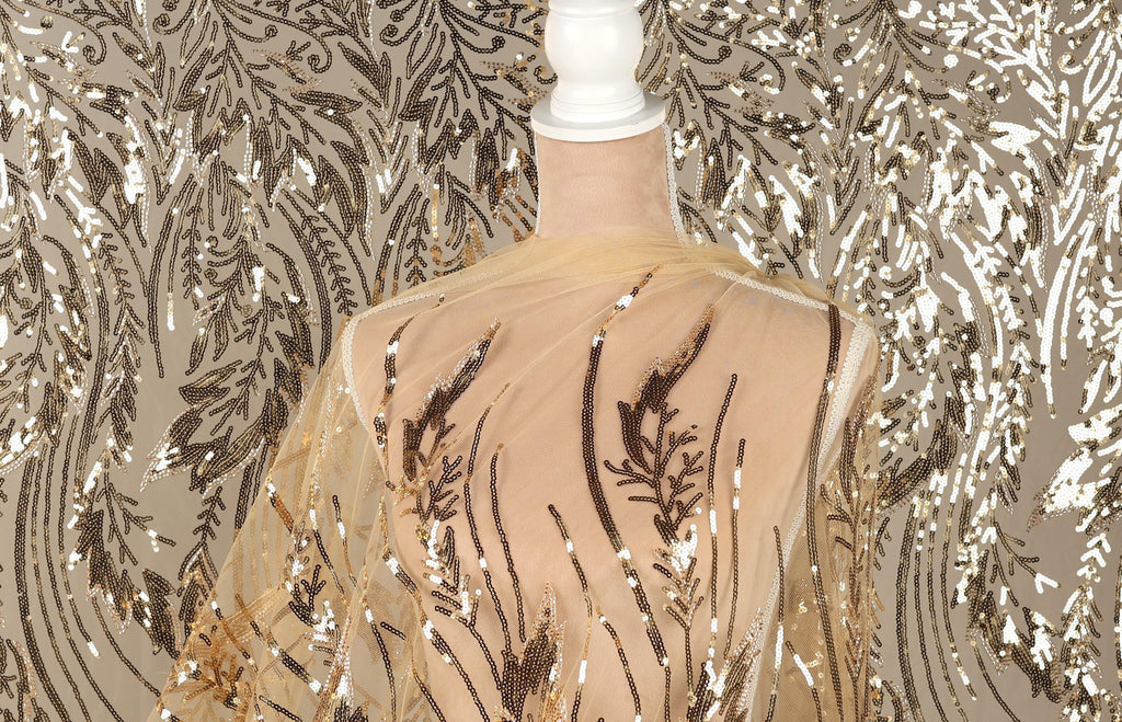 a mannequin wearing a sheer, gold-colored fabric with a floral pattern. The fabric is draped over the mannequin's back, creating a decorative and elegant appearance.