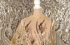 a mannequin wearing a sheer, gold-colored fabric with a floral pattern. The fabric is draped over the mannequin's back, creating a decorative and elegant appearance.