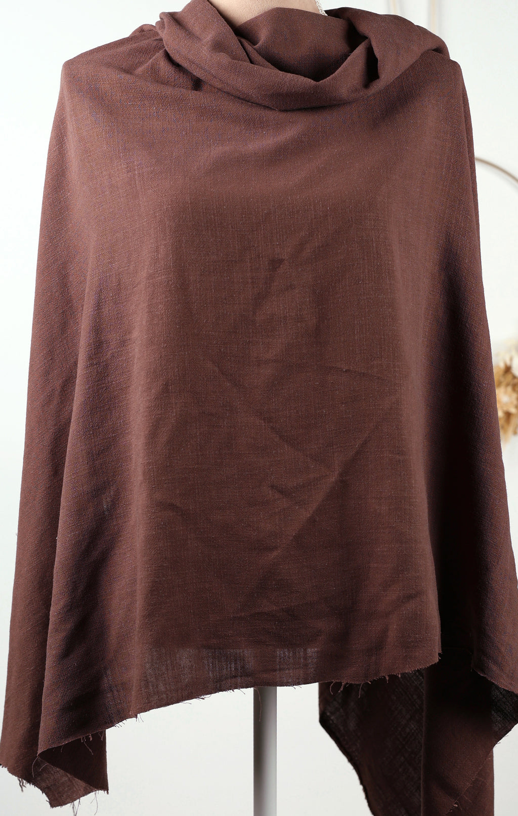 A brown, draped garment is displayed on a mannequin, with a white background.