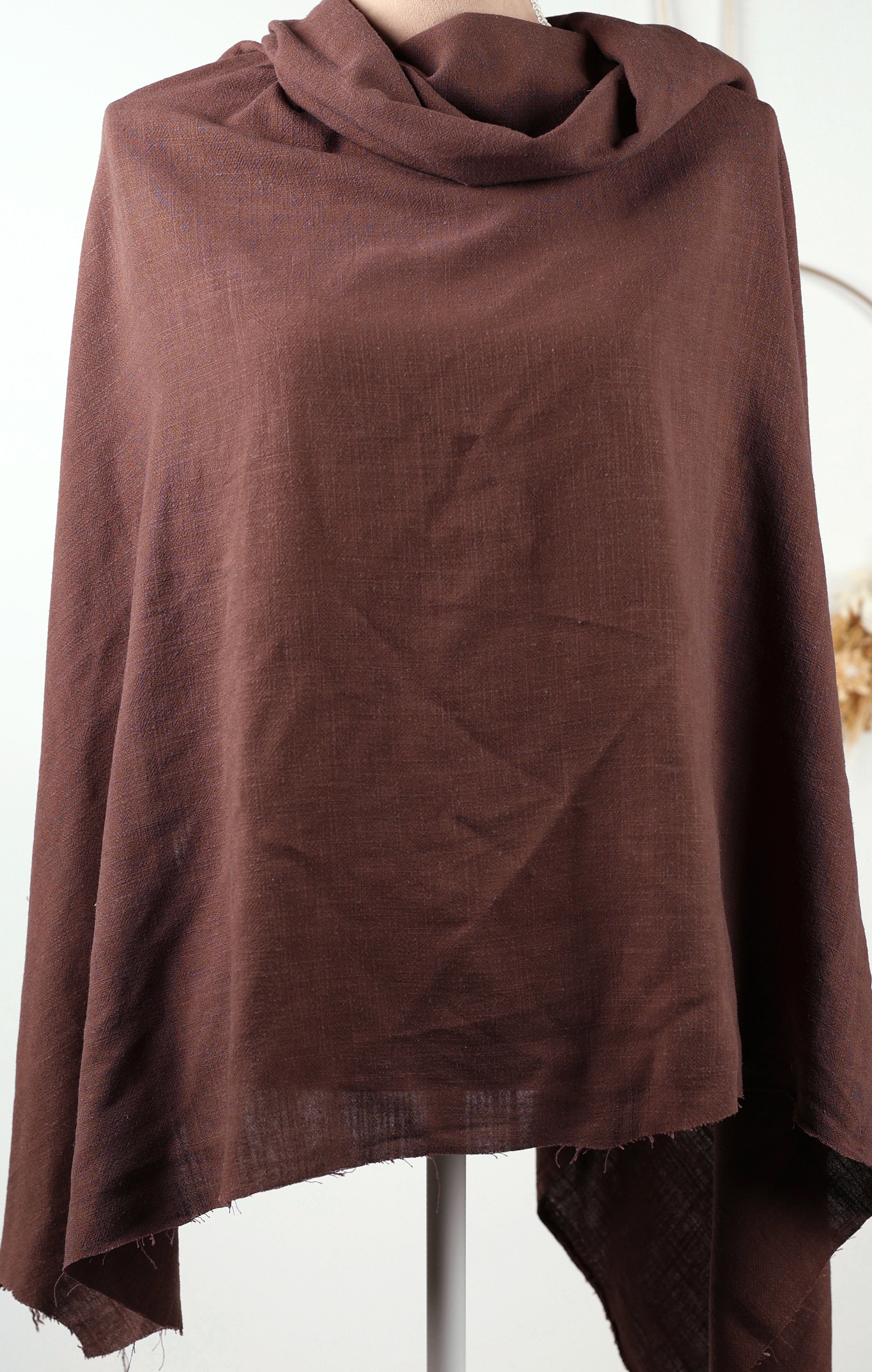 A brown, draped garment is displayed on a mannequin, with a white background.