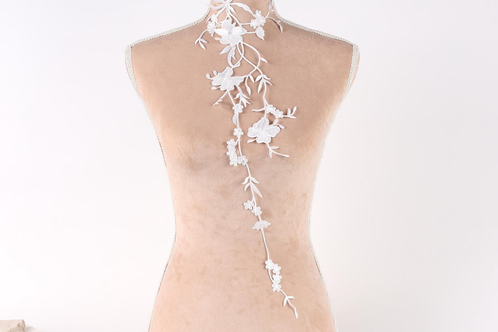 A mannequin with a delicate white lace design on the back, featuring a floral pattern.