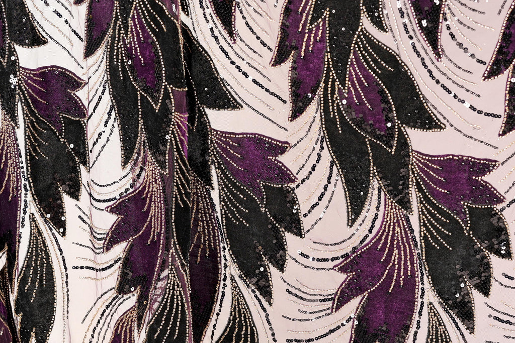a close-up view of a fabric with a repeating pattern of purple and black leaves, accented with gold sequins. The pattern is intricate and detailed, creating a visually striking and textured appearance.