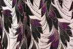 a close-up view of a fabric with a repeating pattern of purple and black leaves, accented with gold sequins. The pattern is intricate and detailed, creating a visually striking and textured appearance.