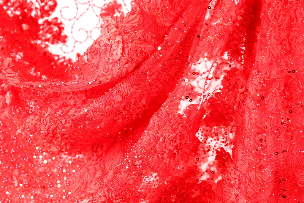 The image is a close-up of a red fabric with a floral pattern, featuring a lot of small details and textures.